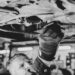 a black and white photo of a man working on a vehicle